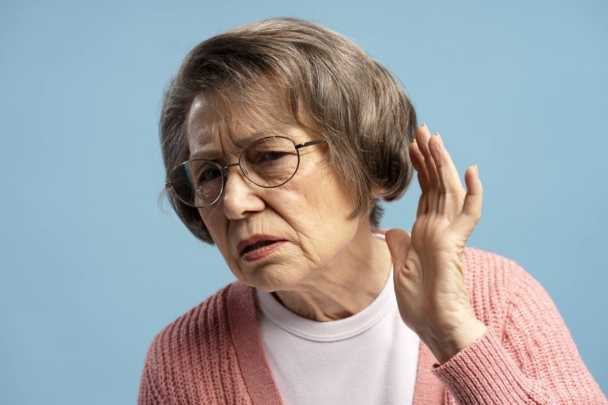 Elderly woman struggling to hear, hand to ear