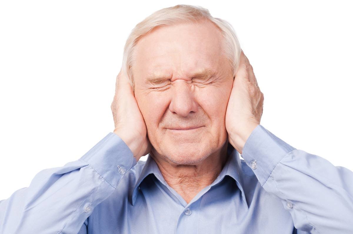 Senior man pressing ears in pain from tinnitus