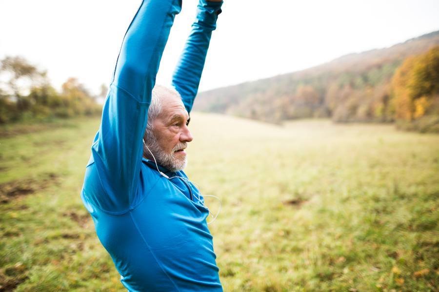 Active mature man stretching outdoors in morning — mobility after 40