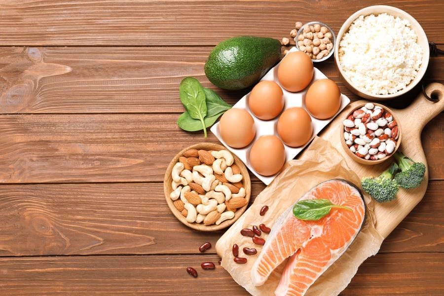 Nerve-healthy foods including salmon, eggs, nuts and leafy greens on wooden surface