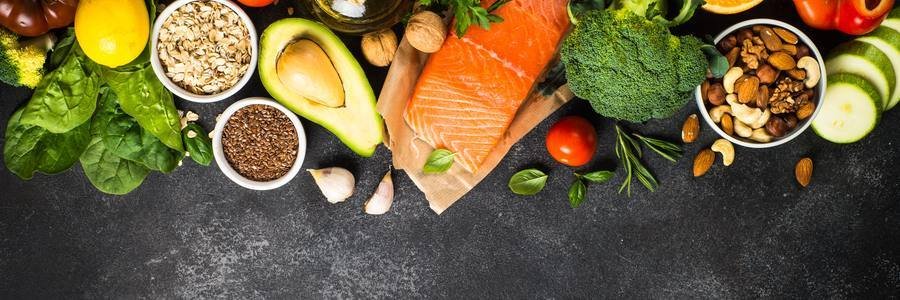 Healthy metabolism-boosting foods including salmon, avocado, nuts, berries, and leafy greens on dark surface