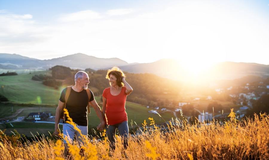 Middle-aged couple walking together on trail at sunset — walking for weight loss after 40