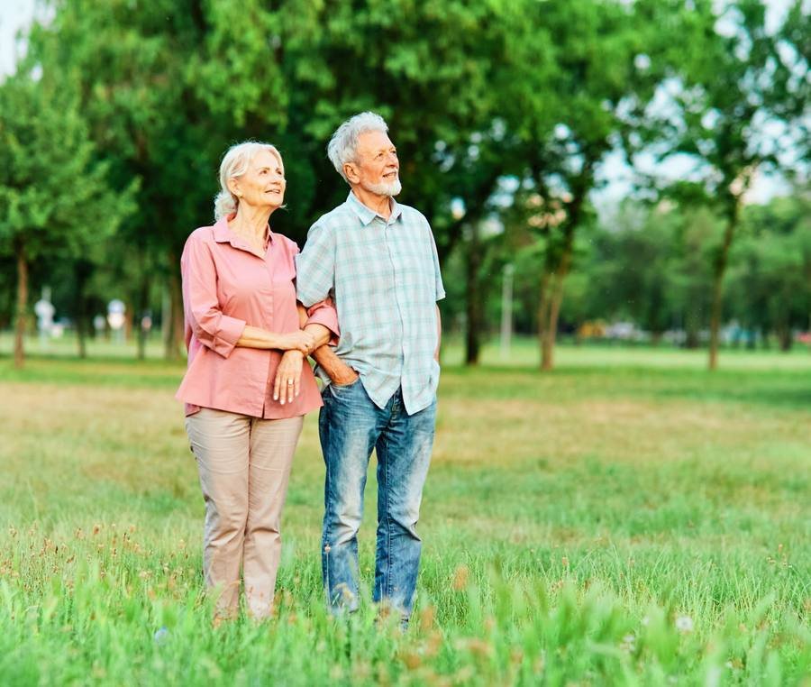 Active senior couple walking in park demonstrating healthy mobility after 40