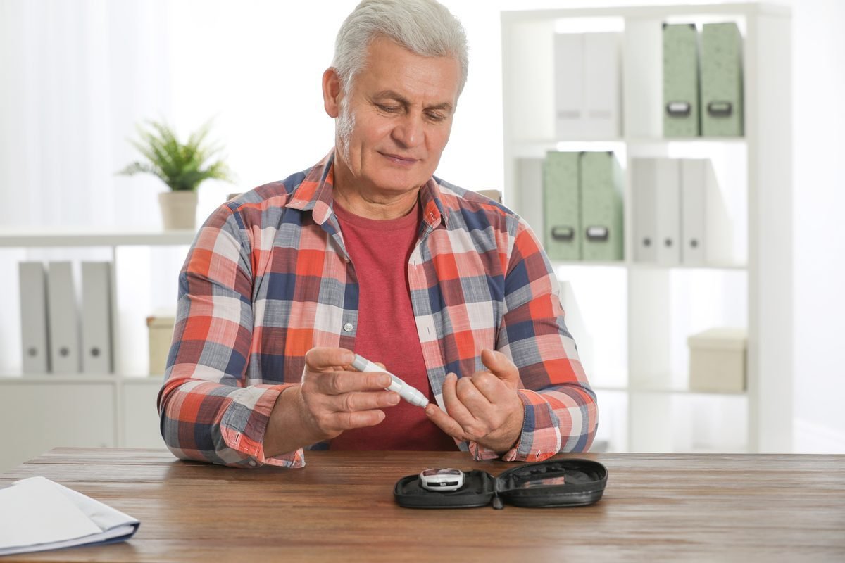 Senior man testing blood sugar levels at home