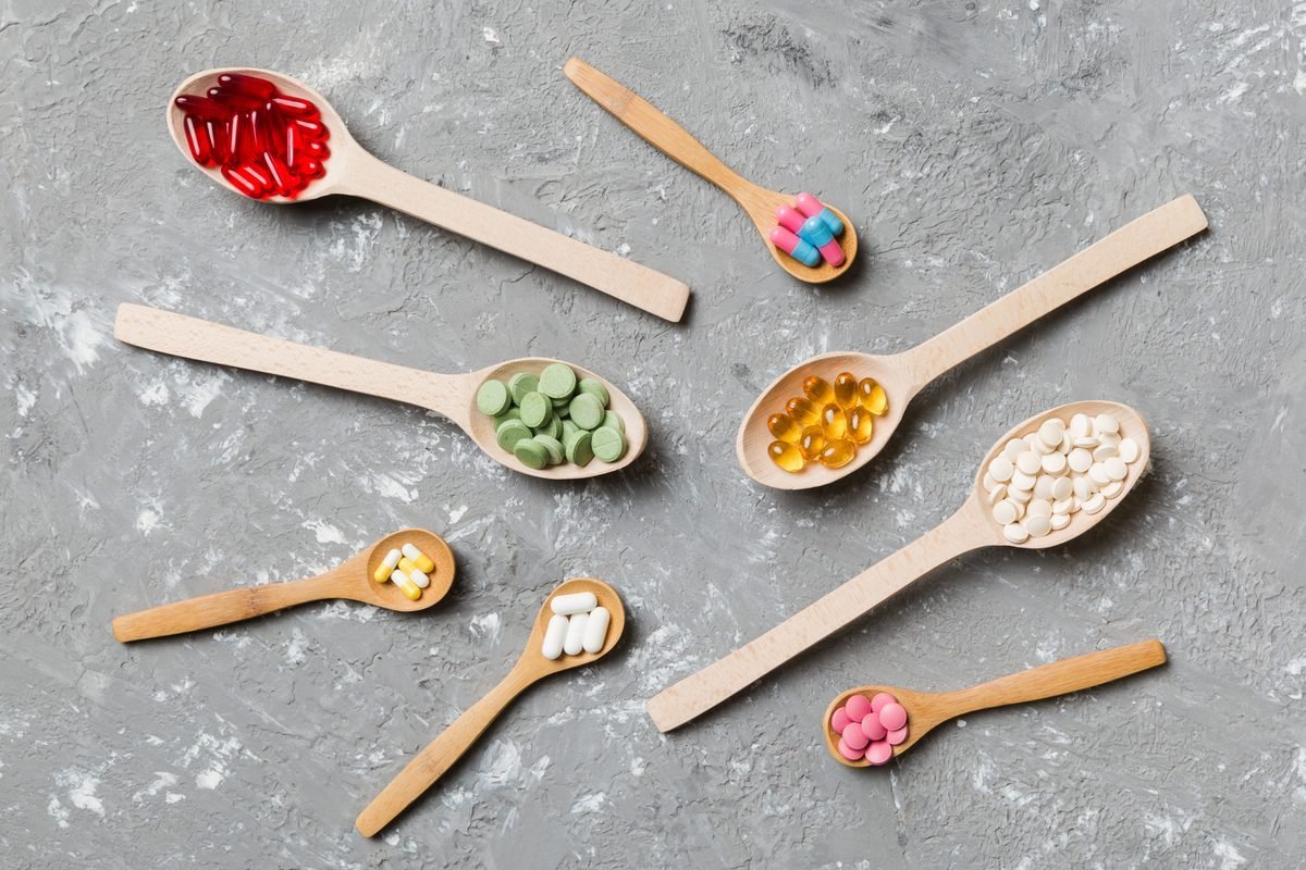 Multiple vitamin and supplement capsules in wooden spoons — combination formulas for blood sugar support