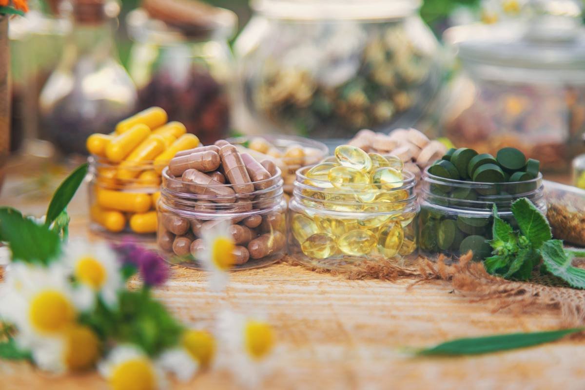 Natural supplement capsules in glass jars with herbs
