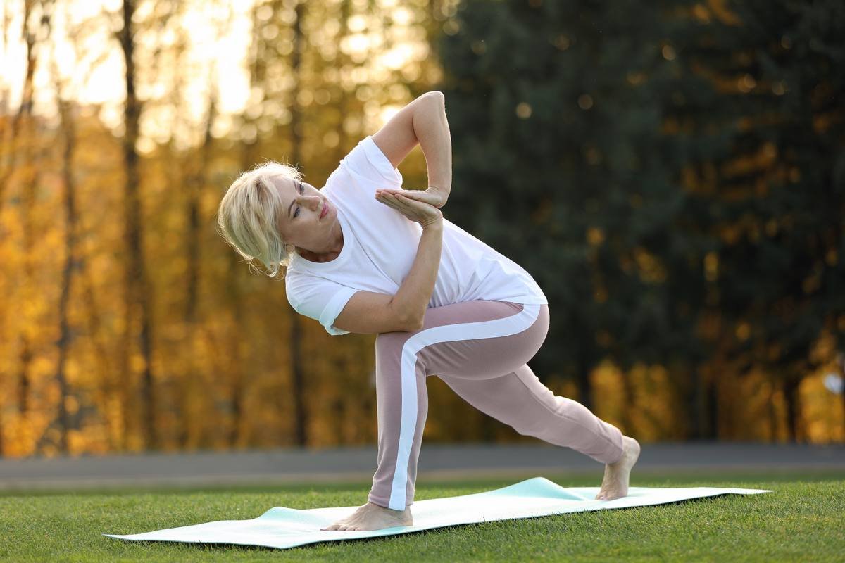 Woman doing yoga stretching exercise in autumn park